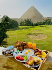 een dienblad met ontbijtproducten met een piramide op de achtergrond bij Glamour Pyramids Hotel in Caïro