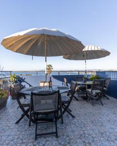 2 tafels en stoelen met parasols op een patio bij Val Paradou - ex - Casa Magnolia in Valparaíso