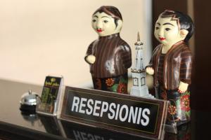 two figurines of two people on a table with a sign at Hotel Pules in Yogyakarta