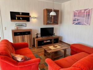 Sala de estar con 2 sillas rojas y TV en Ferienwohnung Seerose en Sassnitz