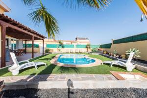 un patio trasero con piscina y una casa en Villa Sophia, en Caleta de Fuste