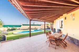 a patio with a table and chairs and a pool at Villa Sophia in Caleta De Fuste