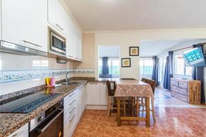 a kitchen with white cabinets and a table with chairs at Villa Sophia in Caleta De Fuste