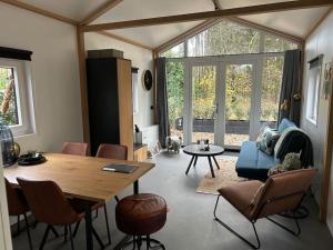 a living room with a table and chairs and a couch at Schitterend 4 persoons Tinyhouse met HOTTUB aan de bossen in Putten 4-16 in Putten