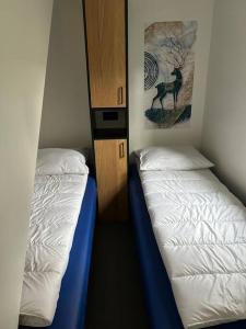 a bedroom with two beds and a cabinet with a deer picture at Schitterend 4 persoons Tinyhouse met HOTTUB aan de bossen in Putten 4-16 in Putten