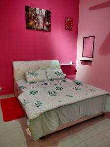 a bedroom with a bed with a pink wall at Amani Homestay in Melaka