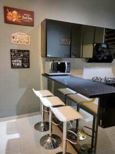 a kitchen with a counter with stools and a microwave at Amani Homestay in Melaka