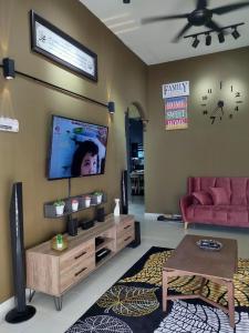 een woonkamer met een bank en een tv aan de muur bij Amani Homestay in Melaka