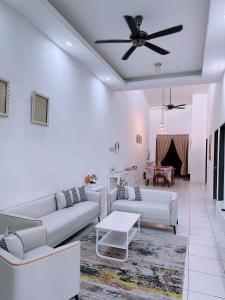 a living room with white furniture and a ceiling fan at Aidee Homestay Taman Ria Height in Tawau