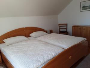 a bed with white sheets and a wooden headboard at FeWo Christine in Bad Buchau