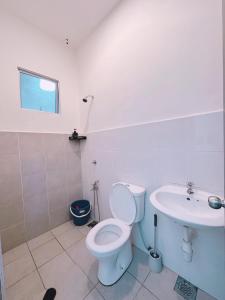 a white bathroom with a toilet and a sink at Aidee Homestay Taman Ria Height in Tawau