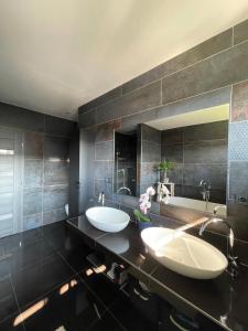 une salle de bain avec deux lavabos et un grand miroir dans l'établissement Stošice Residence, à Liptovský Mikuláš