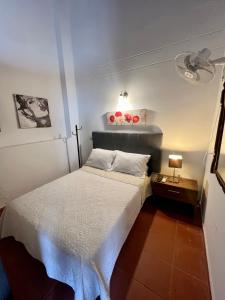 um pequeno quarto com uma cama branca e um candeeiro em Apartamento Familiar Puerta Azul em Santa Cruz de Mompox