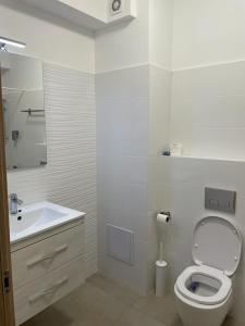 Baño blanco con aseo y lavamanos en Apartament luminos, en Voluntari
