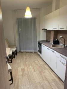 cocina con armarios blancos, fregadero y encimera en Apartament luminos, en Voluntari