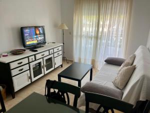 uma sala de estar com um sofá e uma televisão em Apartamento Pinares del Portil a pie de playa em El Portil