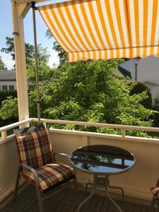 una mesa y una silla en un porche con sombrilla en FeWo Malum, Sonniges Apartment direkt an der Ostsee, en Zierow
