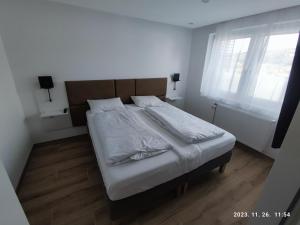 una camera da letto con un letto con lenzuola bianche e una finestra di Apartment Feldkirch a Feldkirch