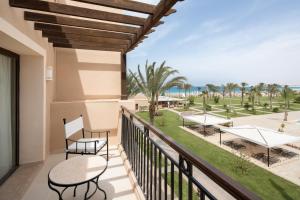 a balcony with tables and chairs and a view of the beach at Jaz Oriental, Almaza Bay in Marsa Matruh