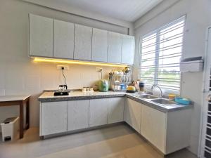 a kitchen with white cabinets and a sink at pen kyu house1 in Kota Samarahan