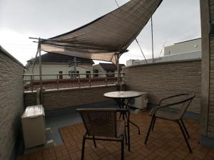 eine Terrasse mit 2 Stühlen und einem Tisch auf dem Dach in der Unterkunft YUKIMARU in in Tokio