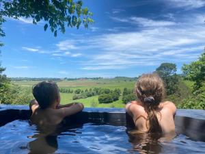 a boy and a girl sitting in a hot tub at Little Fields Country House and Cottages in Howick