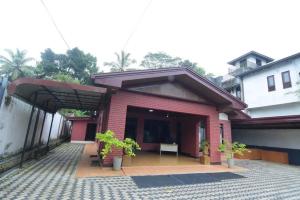 a red brick house with a bench in a courtyard at CHANA BRICKS BUNGALOW in Ratnapura