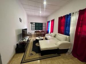 a living room with a white couch and a tv at J Nova LDA in São Tomé