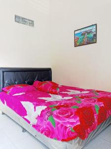 a bed with a pink blanket on top of it at Penginapan Ana Indah in Borobudur +33 photos