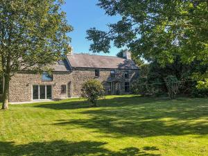 une grande maison en pierre avec une cour herbeuse dans l'établissement Morfa Ganol, à Llangrannog