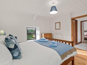 a bedroom with a white bed with blue towels on it at Morfa Ganol in Llangranog