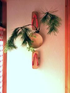 心遊亭ー敬華の間Shin Yu Tei في كانازاوا: زينة عيد الميلاد معلقة على جدار مع فرع شجرة