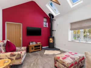 a living room with a red wall with a flat screen tv at Cranford Cottage in Saint Brides