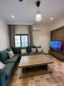 uma sala de estar com um sofá verde e uma televisão em 6/ Antica jabalal-lwebdeh em Amã