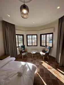 a bedroom with a bed and some chairs and windows at 6/ Antica jabalal-lwebdeh in Amman