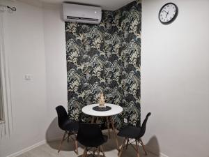a table with chairs and a clock on a wall at Schmidt Apartman Miskolc Belvárosában in Miskolc