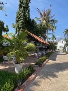 un pabellón con mesas, sillas y palmeras en Fides Boutique Hotel en Luang Prabang