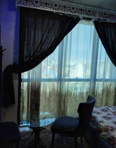 a bedroom with a window with a chair and a table at Luxe Studio Sea View in Oran