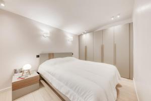 um quarto branco com uma cama grande e uma mesa de cabeceira em 1 Bedroom near Le Bon Marché em Paris