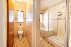 een badkamer met een toilet, een bad en een douche bij Gastehuis 17 in Bloemfontein