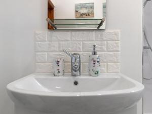 a bathroom sink with two cups and a faucet at The Cwtch in Pembrokeshire