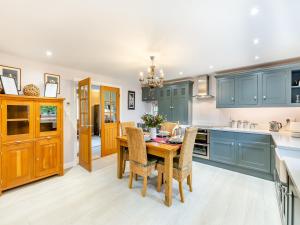a kitchen with blue cabinets and a wooden table and chairs at Adair Cottage in Wigglesworth