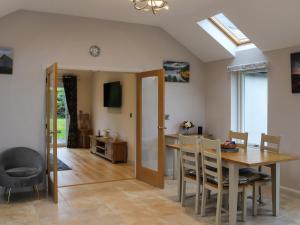 a dining room and living room with a table and chairs at Beudy Wern Goch in Llanuwchllyn