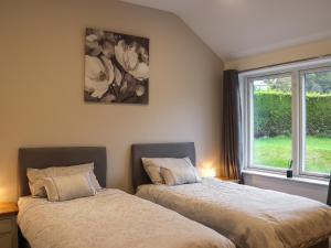 two beds in a room with a window at Beudy Wern Goch in Llanuwchllyn