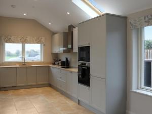 a kitchen with white cabinets and a window at Beudy Wern Goch in Llanuwchllyn