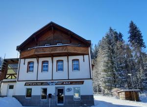 a building with a wooden roof in the snow at Gemütliches Apartment am Gottesberg in Muldenhammer