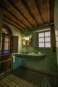 a green bathroom with a sink and a window at Riad Les Idrissides in Fez