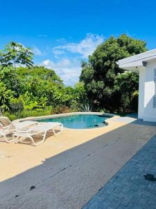 una piscina con 2 sillas blancas y una casa en Cozy family house with pool, en Atenas