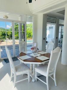 comedor con mesa de madera y sillas blancas en Cozy family house with pool, en Atenas