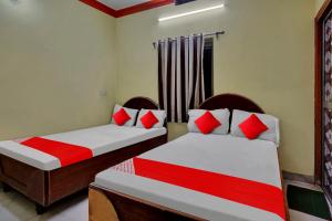 2 Betten in einem Zimmer mit roten und weißen Kissen in der Unterkunft OYO Flagship 81231 Urmila Guest House in Bodh Gaya